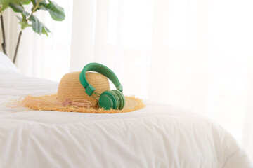 Straw hat and headphones on the bed. Summer travel items preparing for holiday vacation trip. journey planning