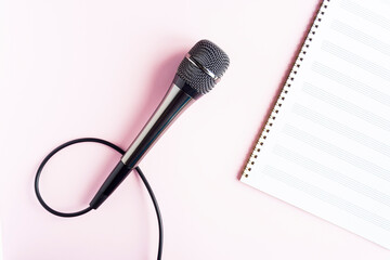 Microphone on a blank musical white sheet close up. Singing, writing music, karaoke online, creativity, vocals concept, symbol. Singing lessons