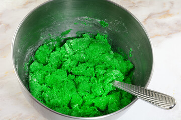 Making batter for green Saint Patrick`s Day cookies by mixing ingredients of flour butter egg and green food coloring stainless steel mixing bowl