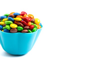 Rainbow Colored Candy Coated Chocolate Buttons in a Fun Blue Bowl Isolated on a White Background