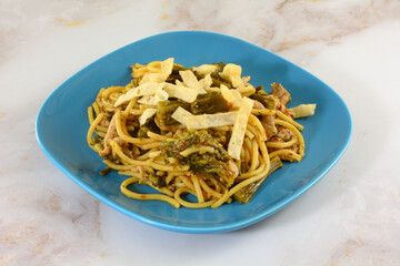 Lunch plate of sliced pork and broccoli on lo mein noodles with crunchy wonton strips in top