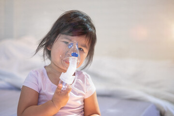 Closeup asian face little children girl sick he using steam inhaler nebulizer mask inhalation...
