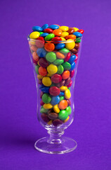 Glass Filled with Rainbow Colored Candy Coated Chocolate Buttons