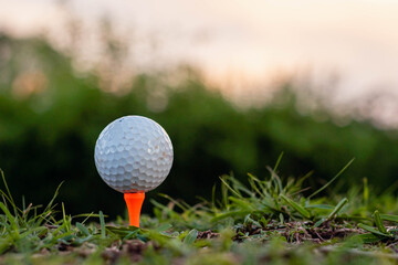 close-up of golf ball and club on green with sunset light