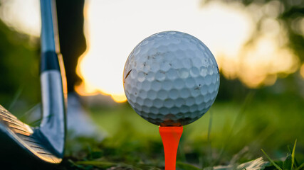 close-up of golf ball and club on green with sunset light