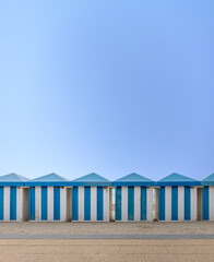 Vintage blue and white striped beach huts against clear sky. Copy space.