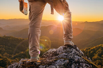 Hiker standing on top mountain sunset background. Hiker men's hiking living healthy active lifestyle. - Powered by Adobe