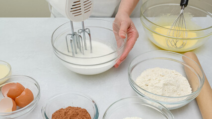Chocolate cake step by step recipe. Woman hands beating egg whites with mixer