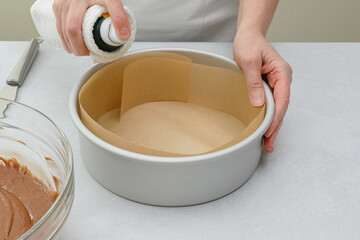 Chef using oil spray onto prepared baking pan. Chocolate cake step by step recipe