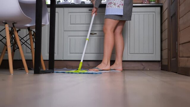 Woman Cleaning the Floor with Mop in the Kitchen while Doing Cleaning at Home. Slow Motion. Household Chores and Housekeeping Concept