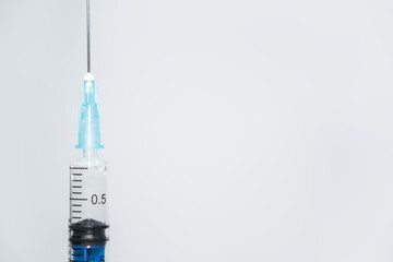 Crop one single syringe with dose of medicine or vaccine on white or gray background with a place for the text: vaccinations against influenza coronavirus, side view, soft focus, selective focus