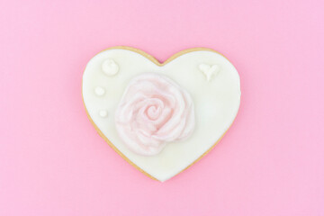 Decorated heart shaped organic cookie with beautiful rose on color background, top view. Valentine's day treat