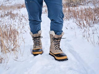 legs of male hiker or hunter in heavy snow boots on a trail in northern Colorado at foothills of Rocky Mountains