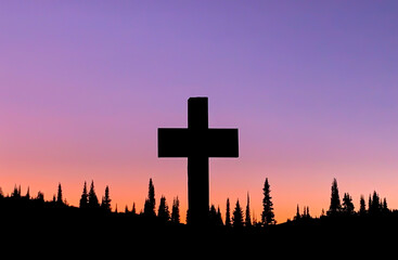 Silhouette of cross and Pine trees against gradient sunset without clouds