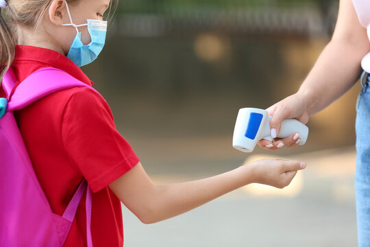 Teacher measuring temperature of pupil. Coronavirus epidemic