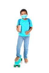 Little African-American schoolboy in medical mask and with skateboard on white background. Coronavirus epidemic