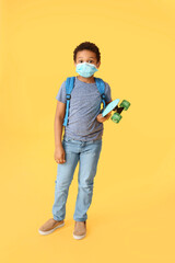 Fototapeta premium Little African-American schoolboy in medical mask and with skateboard on color background. Coronavirus epidemic
