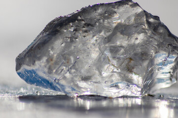 Frozen shiny ice cube melting in the sun with nice reflections in the transparent ice in arctic...