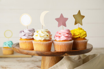 Tasty cupcakes with stylish toppers on wooden background