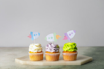 Tasty cupcakes with stylish toppers on light background