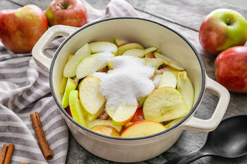 Cooking pot with cut apple and sugar, closeup