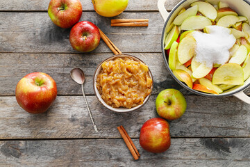 Bowl with jam and pot with cut apples on wooden background