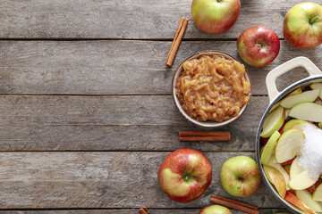 Bowl with jam and pot with cut apples on wooden background