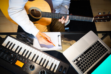 top view of male songwriter writing a song with laptop computer and keyboard on desk. songwriting concept - obrazy, fototapety, plakaty