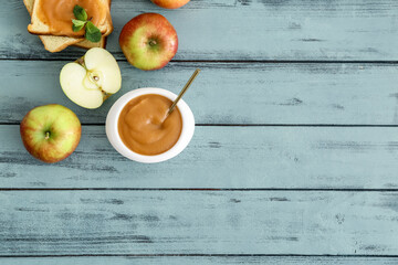Bowl with sweet apple jam on color wooden background