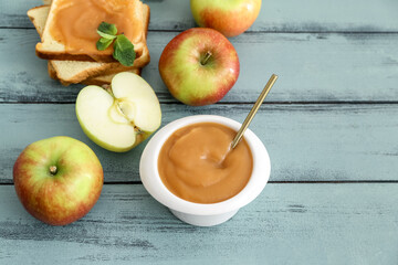 Bowl with sweet apple jam on color wooden background