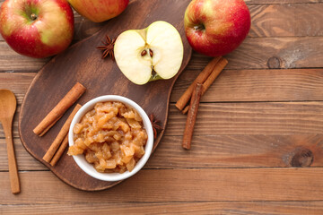 Bowl with sweet apple jam and cinnamon on wooden background