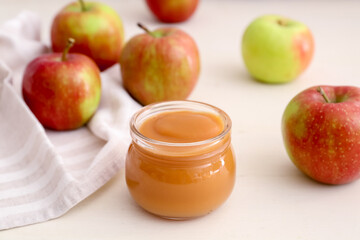 Jar with sweet apple jam on light background