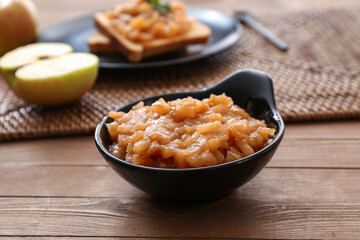 Bowl with sweet apple jam on wooden background