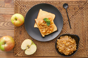 Bowl with sweet apple jam and toasts on wooden background