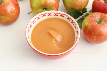 Bowl with sweet apple jam on light background