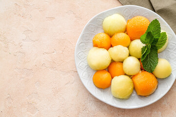 Plate with sweet melon balls on color background