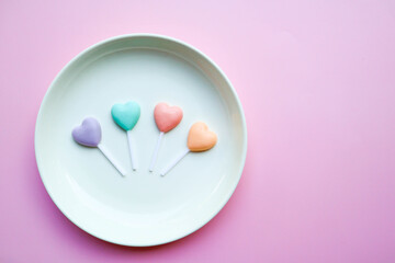 Heart shape chocolate in pastel color on the white plate of pink background with copy space - Love and cute concept 