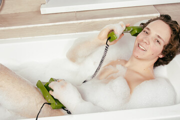 Relax in the bathroom. Young attractive guy talking on the phone.