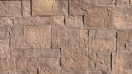 a fragment of a wall or fence finished with red natural stone with preserved texture, rectangular tiles of different sizes made of natural red stone for external surfaces, graphic stone resource
