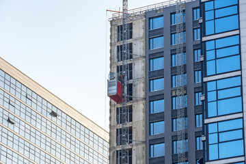 Construction elevator outside the facade of a multi-storey building under construction.