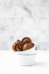 Chocolate ice cream balls in two white bowls, light and bright background