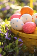Easter holiday.Easter eggs in a yellow basket in purple spring flowers on a blurred spring garden...