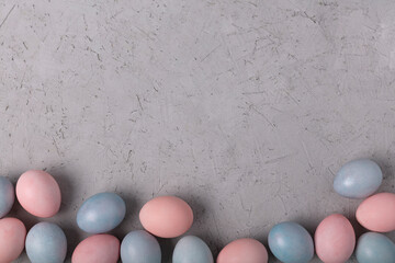 Pattern of chicken painted pink and blue Easter eggs on grey background.