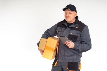 Home delivery of goods. The smiling courier looks at the camera. A man with boxes and a tablet PC delivers an order to a customer. Delivery service.