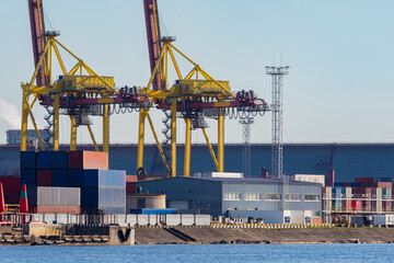 Commercial port. View of the warehouse in the port and gantry cranes. Cranes and containers with cargo in the port. Transportation of goods by water transport. Loading and unloading operations.