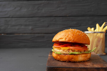 Fresh burger and fries on black wooden background