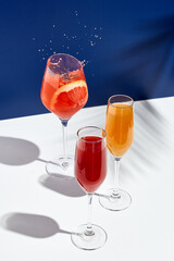 Aperol drink and bellini cocktail on white table with blue background. Sunshine and palm leaf...