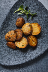 Roasted potato on dark restaurant plate. Vintage gray table. Gourmet food restaurant menu