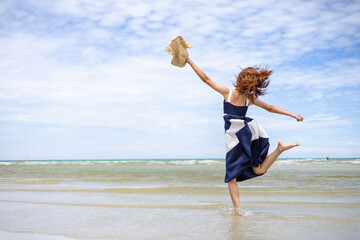 Obraz premium Woman barefoot jump in the water on summer along wave of sea water and sand on the beach.