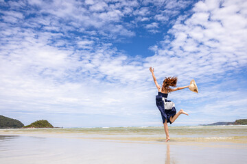 Woman barefoot jump in the water on summer along wave of sea water and sand on the beach.